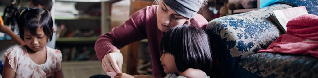 A member of the discipleship training school teaching a child how to read the bible.
