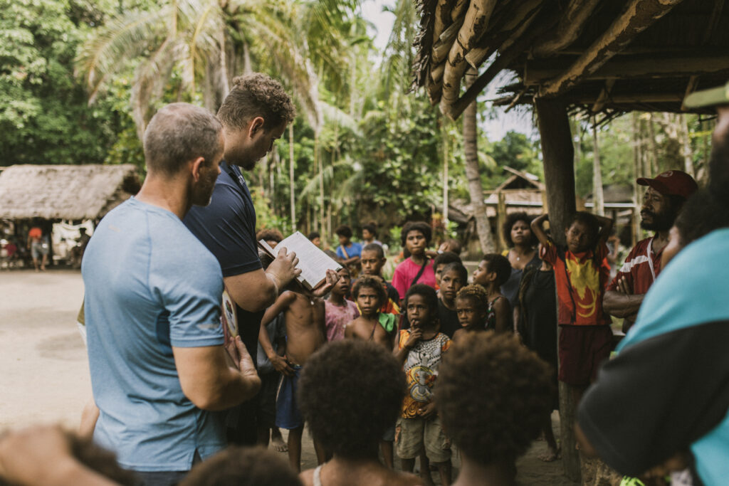 Are you called to ministry? missionaries sharing the gospel with children under a pavilion made of nearby trees.